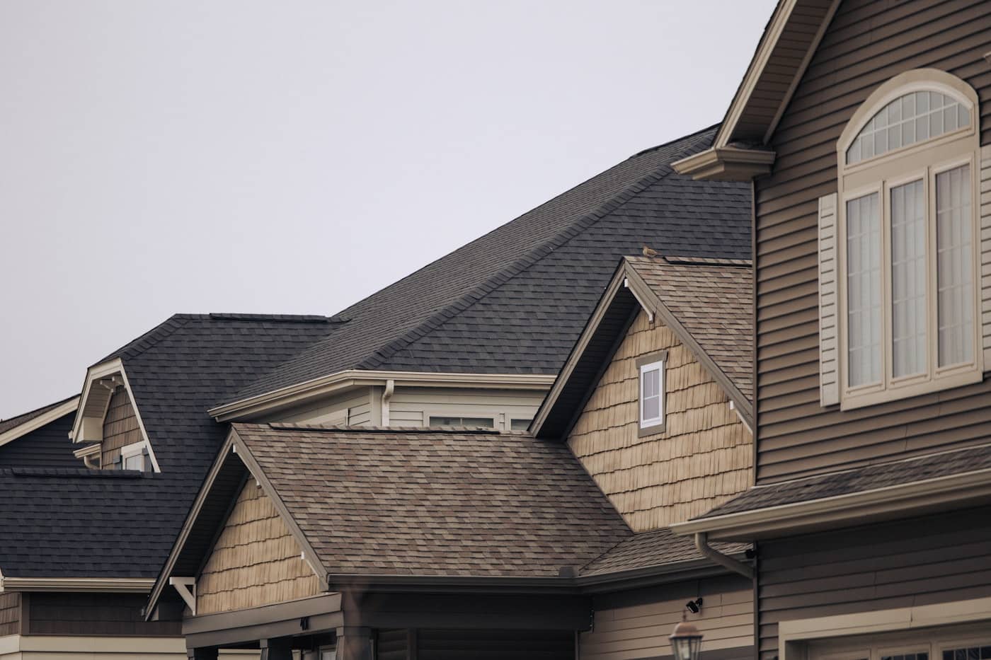 Layered gables and hips of a composition-shingle roofline, courses running clean and straight